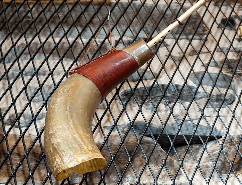 Representación de instrumento de vento con corno.